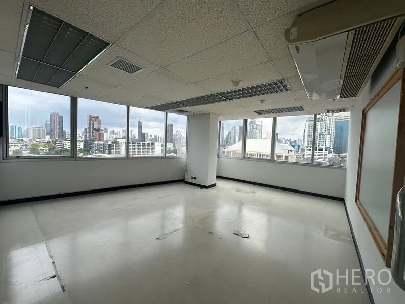 Office Space for rent - Corner office with wide city views through multiple windows and suspended ceiling lights.