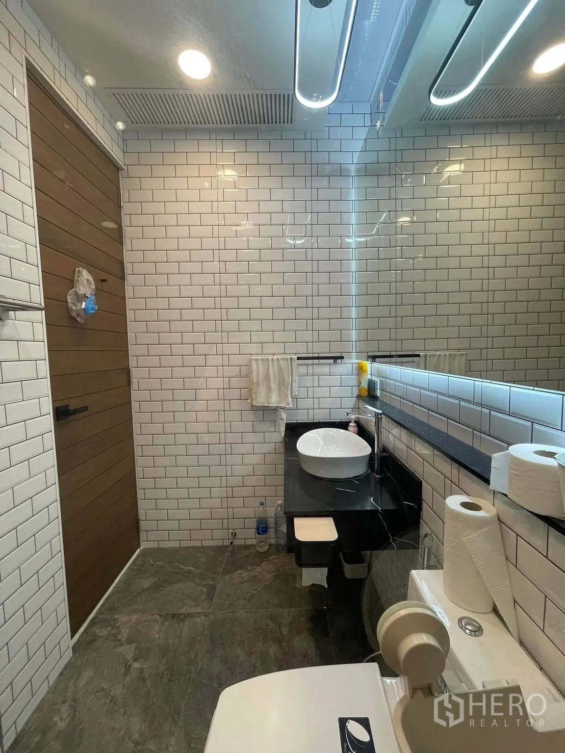Home Office for rent or sale in Bang Kapi, Bangkok - Modern bathroom with white subway tiles, vessel sink, black countertop and large mirror.
