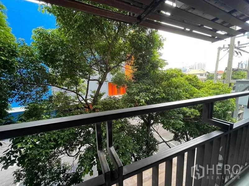 Condominium for rent - Shaded balcony with metal railing overlooking leafy trees and neighborhood.