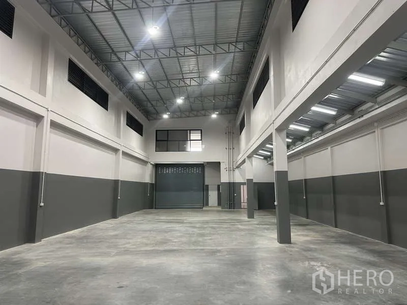 Factory for rent or sale in Bang Bua Thong, Nonthaburi - Warehouse view toward the roller shutter and internal office windows.