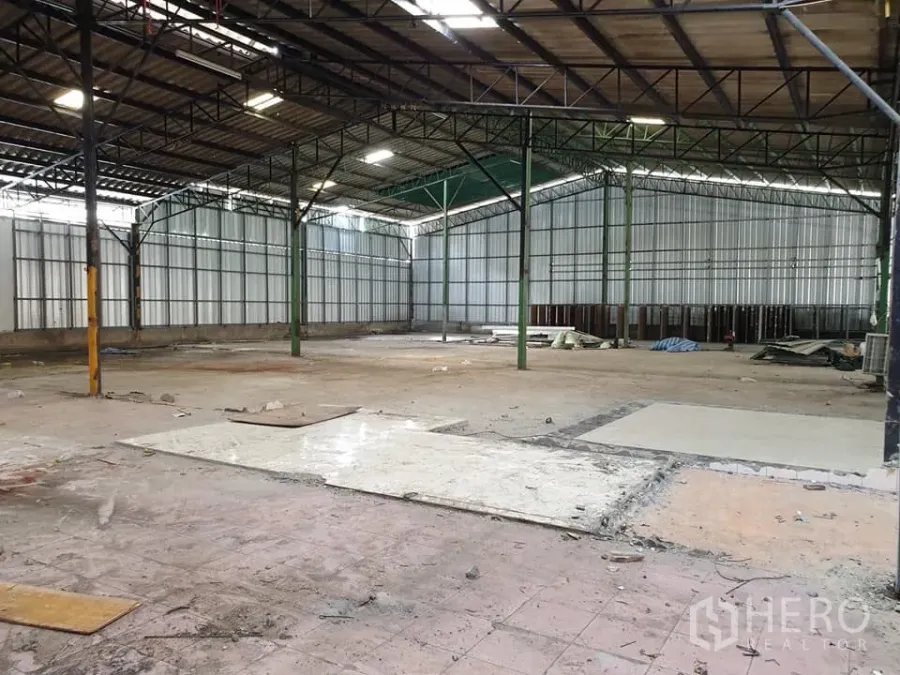 Warehouse for rent in Mueang Nonthaburi, Nonthaburi - Spacious warehouse interior with steel truss roof, high ceilings, metal sheet walls and open concrete flooring.