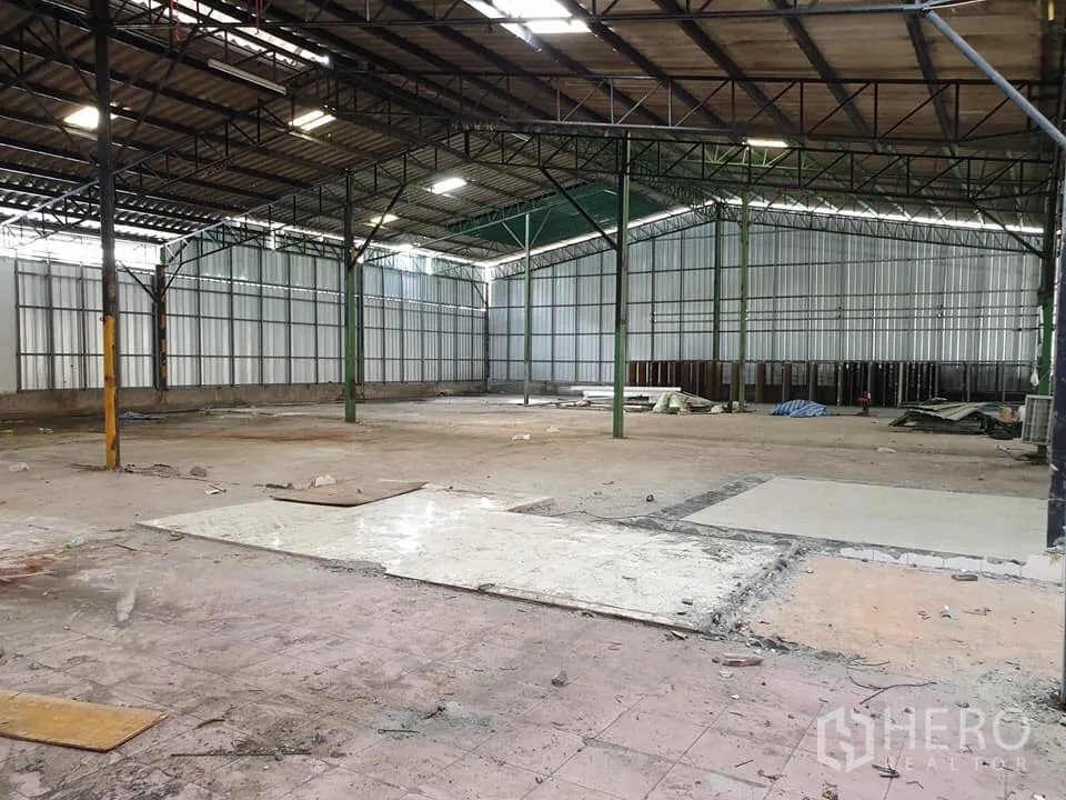 Warehouse for rent in Mueang Nonthaburi, Nonthaburi - Spacious warehouse interior with steel truss roof, high ceilings, metal sheet walls and open concrete flooring.