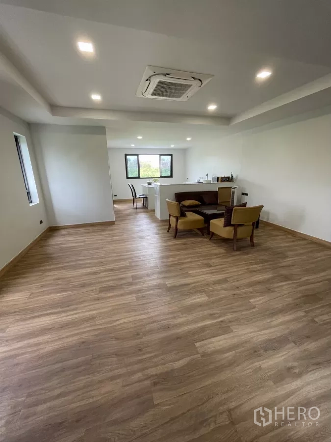 Home Office for rent in Khan Na Yao, Bangkok - Large multipurpose room with wood floors, ceiling AC and a seating area beside a pantry.