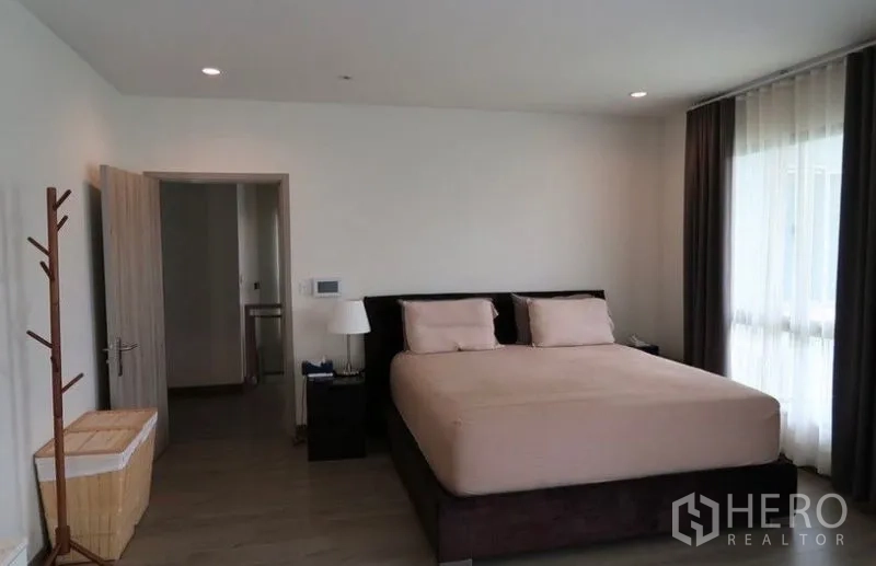 Detached House for rent or sale in Saphan Sung, Bangkok - Spacious master bedroom with king bed, wood flooring, and large curtained windows.