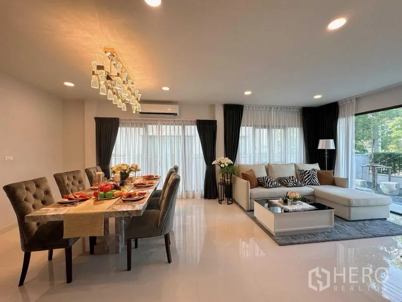 Detached House for rent or sale - Open-plan living and dining area with chandelier, sectional sofa and full-height windows.