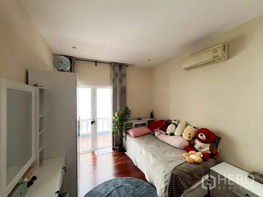 Detached House for rent in Phra Khanong, Bangkok - Cozy bedroom with daybed, air conditioner, and doors to the balcony.