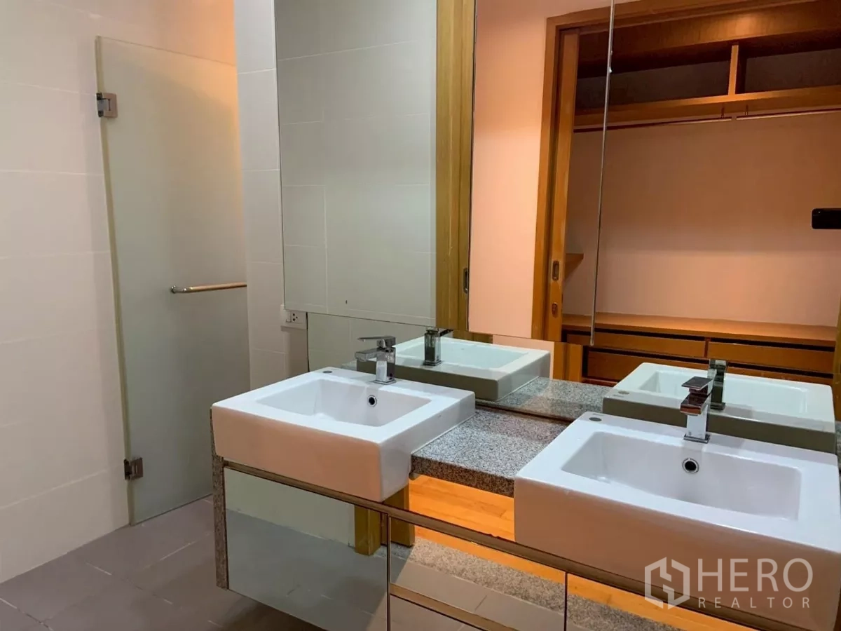 Condominium for rent in Khlong Toei, Bangkok - Bathroom with double square sinks, large mirror and frosted glass door.