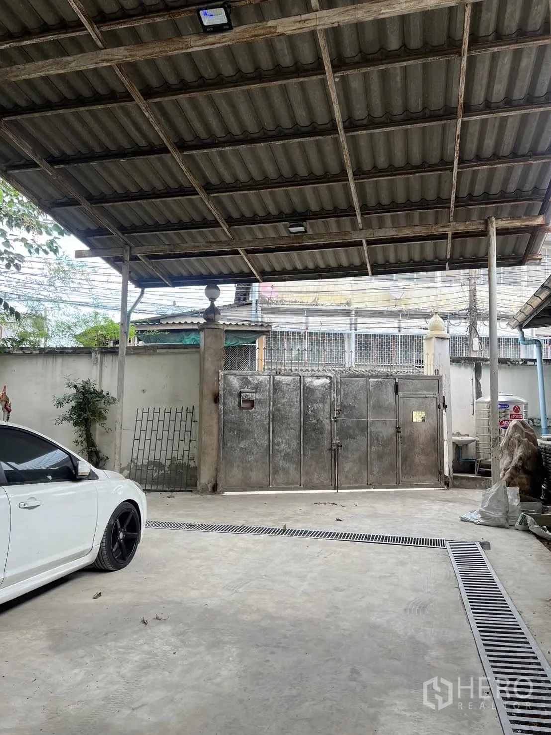 Warehouse for rent in Phra Pradaeng, Samut Prakan - Covered driveway with metal gate and drainage channel beside the loading area.