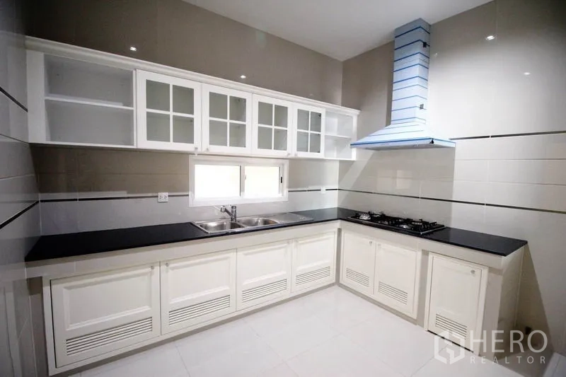 Detached House for rent or sale - Separate Thai kitchen with gas hobs, range hood, glass-front cabinets and black countertops.