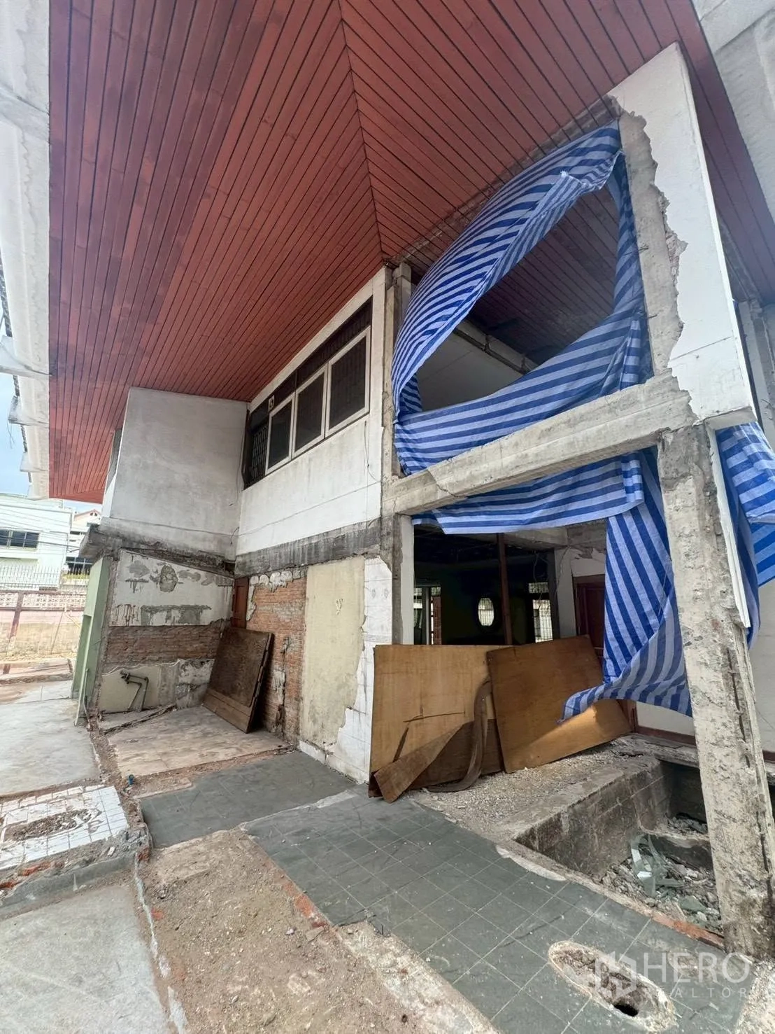 独栋房屋 for rent or sale in Watthana, Bangkok - 房屋外立面局部在翻修中，结构裸露并覆盖防护布。