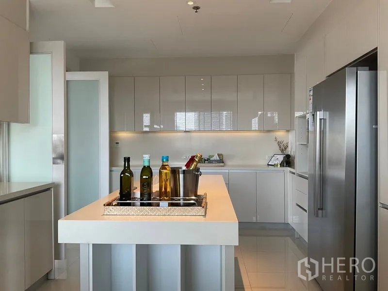 Apartment for rent in Sathon, Bangkok - Kitchen with island countertop and full‑height cabinets under soft lighting.