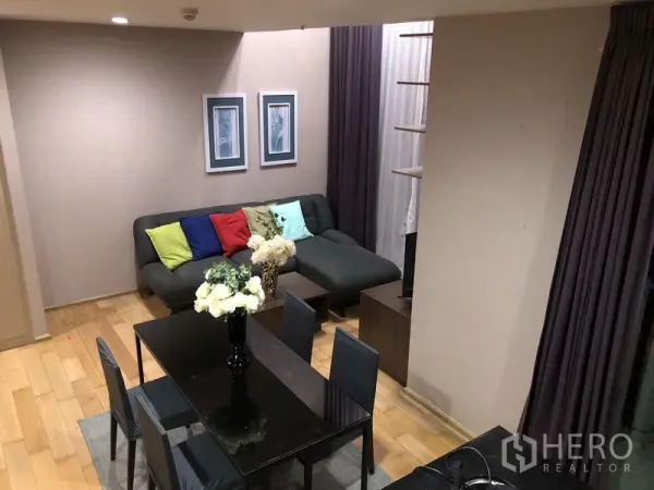 公寓 出租或出售在Khlong San, Bangkok - 从阁楼俯瞰客厅与餐区，彩色抱枕与高挑窗帘醒目。