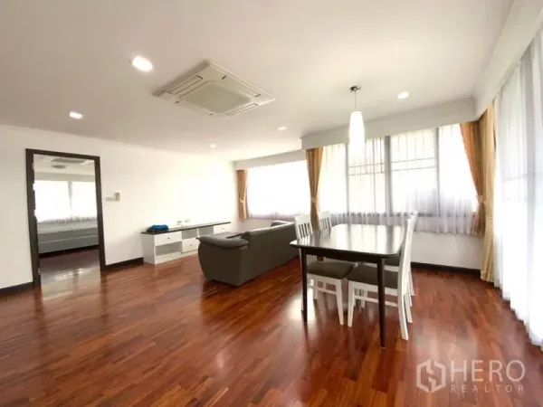 公寓 出租在Watthana, Bangkok - 宽敞起居与用餐区，天花机空调、转角飘窗与温润木地板。