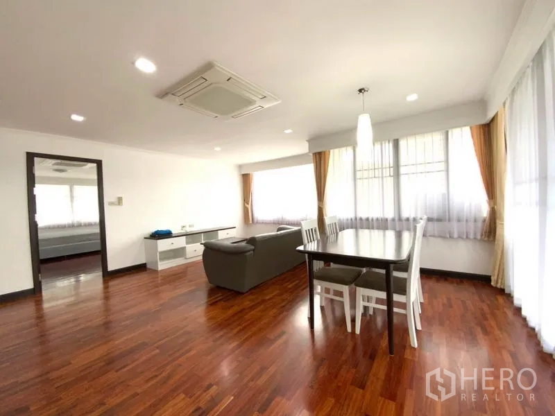 公寓 出租在Watthana, Bangkok - 宽敞起居与用餐区，天花机空调、转角飘窗与温润木地板。
