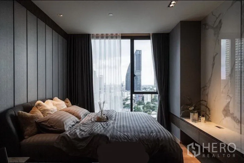Condominium for rent in Khlong Toei, Bangkok - Bedroom featuring large window with city view and marble feature-wall console.