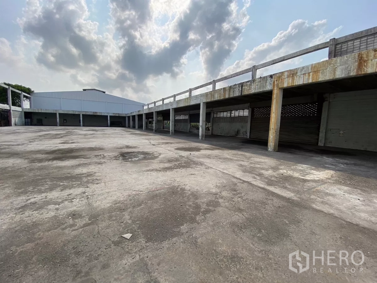 Factory for sale in Bang Phli, Samut Prakan - Angled view of open yard with long canopies and perimeter bays.
