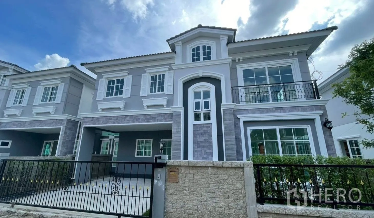 Semi-detached House for rent in Mueang Samut Prakan, Samut Prakan - Exterior of modern semi-detached house with gated driveway, balcony and white-framed windows.