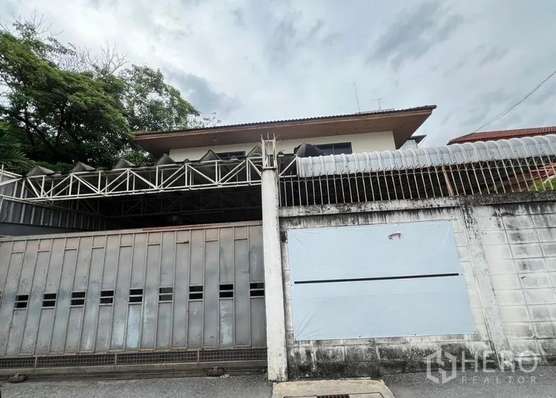 Detached House for rent in Khlong Toei, Bangkok - Gated two-storey detached house in Ekkamai with high perimeter wall and metal gate.