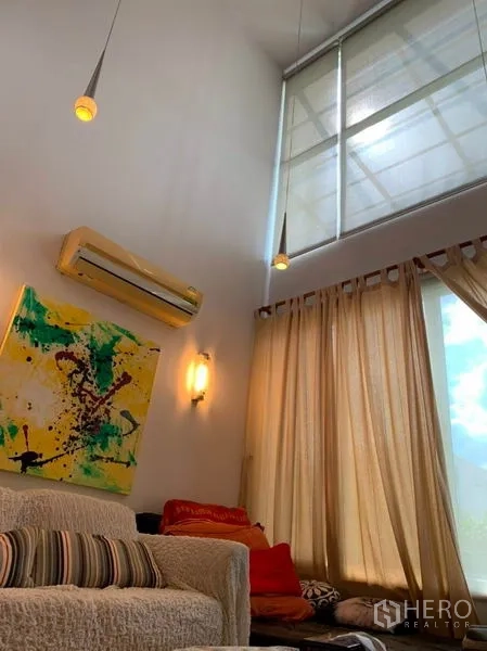 Detached House for sale in Suan Luang, Bangkok - High-ceiling sitting area with tall windows, curtains, split air-conditioning and modern pendant lights.