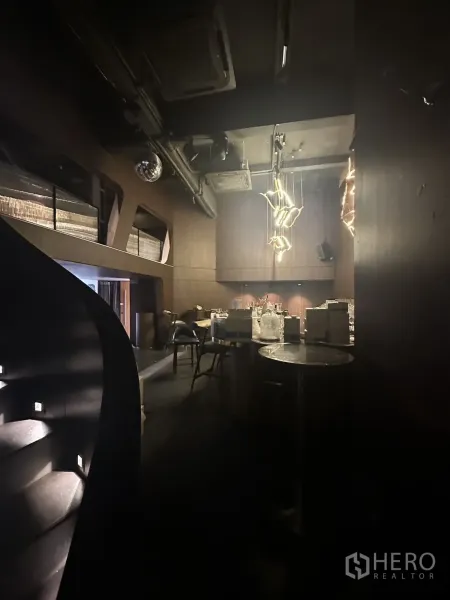 Shophouse for rent in Watthana, Bangkok - Staircase view toward a double-height bar with wood walls and designer lights.