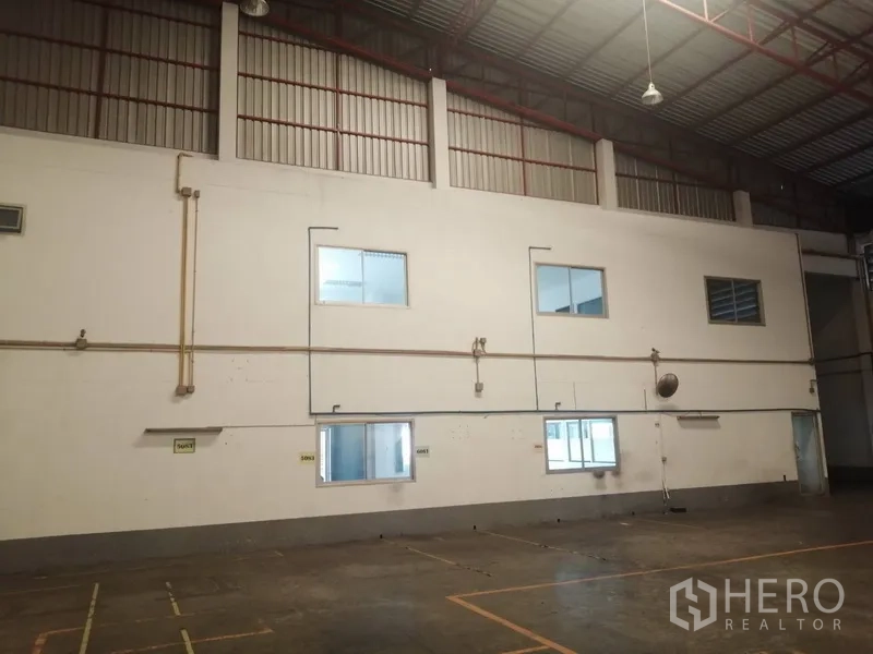 Factory for rent or sale in Bang Phli, Samut Prakan - Warehouse side elevation showing high windows, metal roof and ventilated lighting.