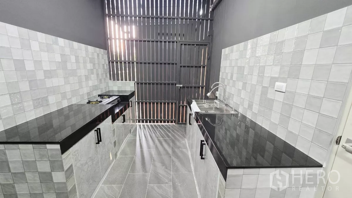 独立式住宅 出租在Prawet, Bangkok - 独立泰式厨房，瓷砖墙面，黑色台面与炉灶。