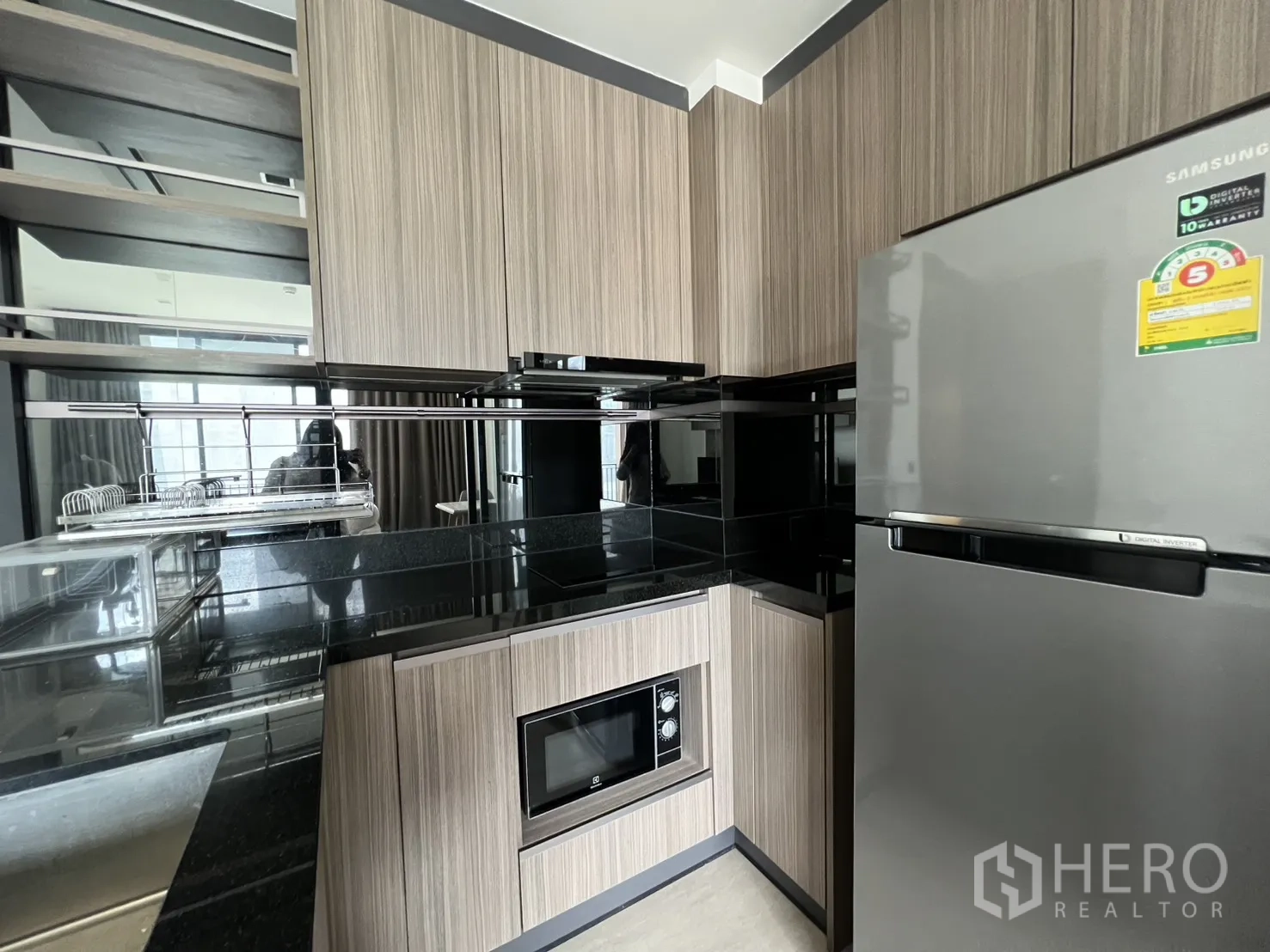 คอนโด for rent in Watthana, Bangkok - มุมครัวที่มีตู้เย็นสแตนเลส ตู้ไม้ และผนังกระจกเงา.