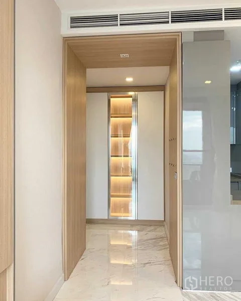 Condominium for rent or sale in Bang Rak, Bangkok - Hallway with illuminated display cabinet and marble flooring.