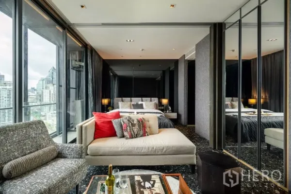 Condominium for rent or sale in Khlong Toei, Bangkok - Bedroom with mirrored wardrobes and cozy sofa seating overlooking the city.