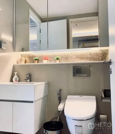 公寓 出租在Watthana, Bangkok - 现代浴室，悬挂式洗手台、镜柜与带喷枪马桶。