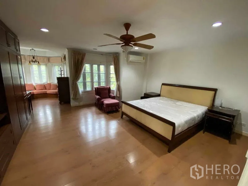 Townhouse for rent or sale in Mueang Samut Prakan, Samut Prakan - Spacious master bedroom with ceiling fan, seating nook and large windows.