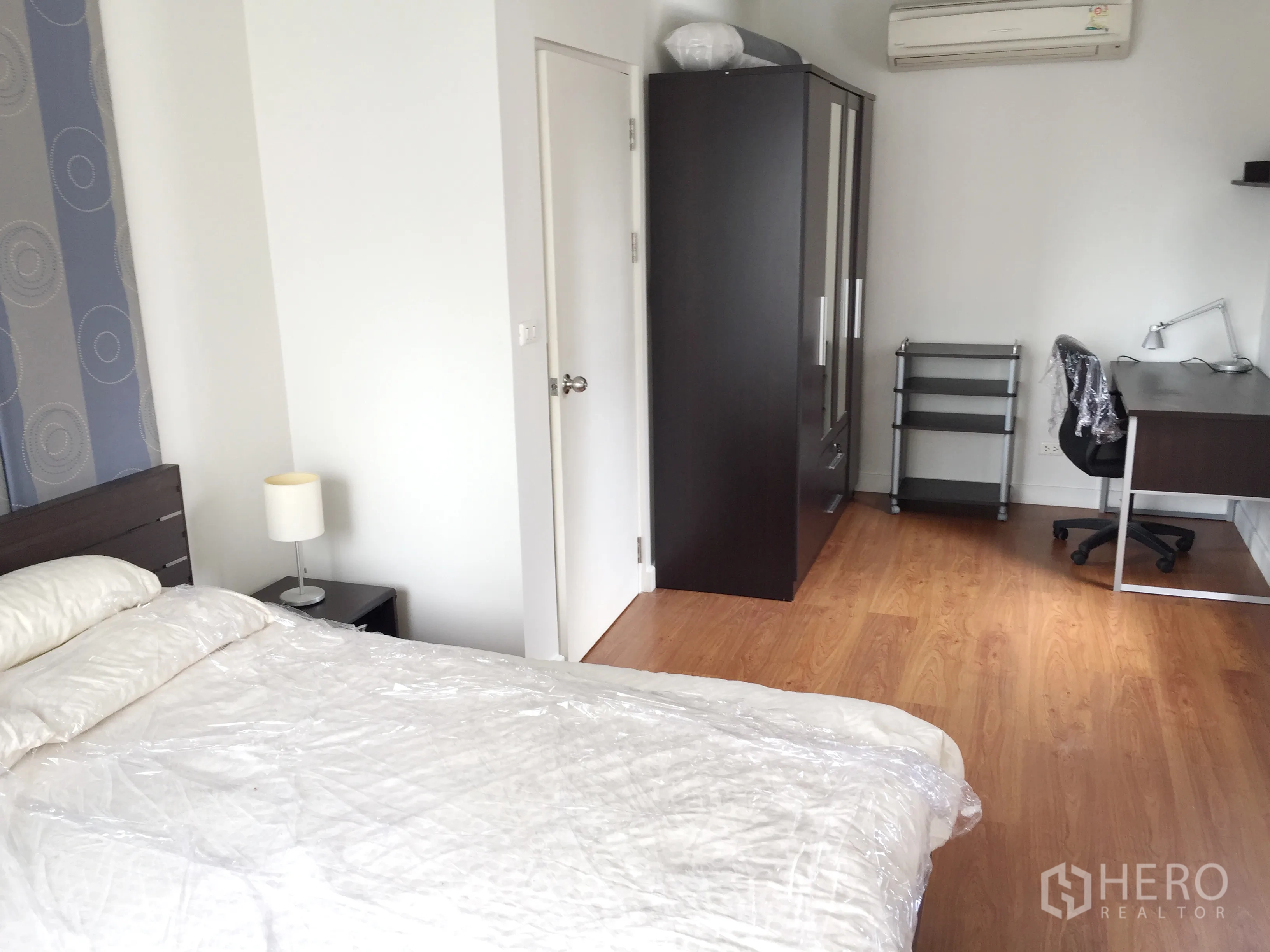 Condominium for rent in Khlong Toei, Bangkok - Bedroom corner with wardrobe, study desk and chair, wood floors and air conditioner.