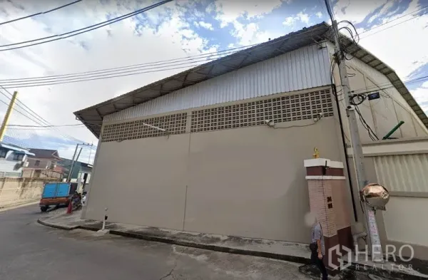 คลังสินค้า ให้เช่าในRat Burana, Bangkok - มุมมองด้านนอกโกดังย่านราษฎร์บูรณะ กรุงเทพฯ หลังคาเมทัลชีทสูง ผนังคอนกรีต และสายไฟฟ้าริมถนน