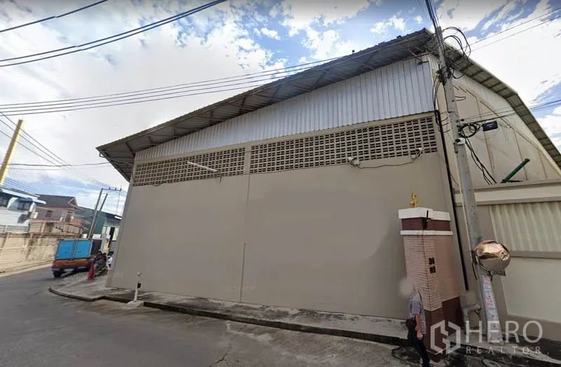 คลังสินค้า ให้เช่าในRat Burana, Bangkok - มุมมองด้านนอกโกดังย่านราษฎร์บูรณะ กรุงเทพฯ หลังคาเมทัลชีทสูง ผนังคอนกรีต และสายไฟฟ้าริมถนน