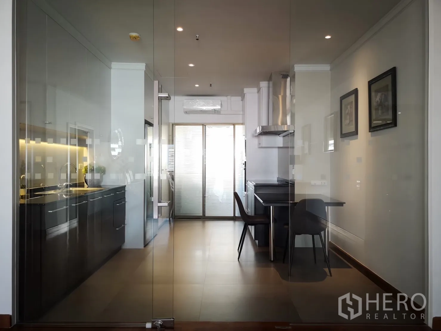 Condominium for rent in Bangkok - Kitchen seen through glass doors with breakfast table and range hood.