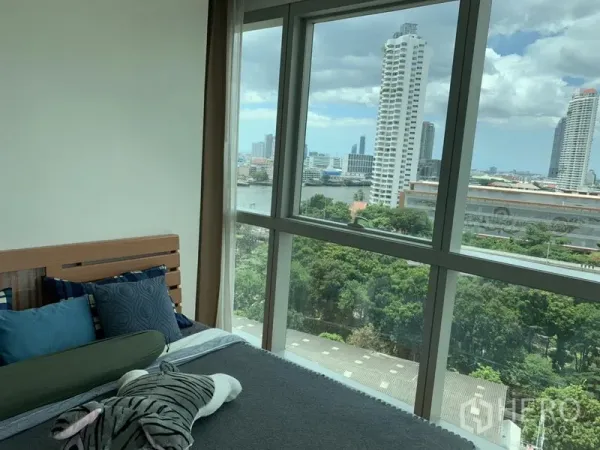 公寓 出租或出售在Khlong San, Bangkok - 卧室宽窗，可眺望河畔高楼与树梢景致。