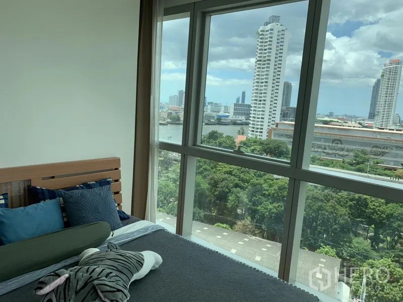 公寓 出租或出售在Khlong San, Bangkok - 卧室宽窗，可眺望河畔高楼与树梢景致。