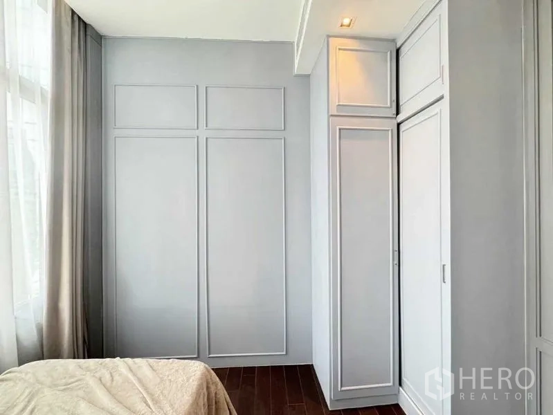 Condominium for rent in Watthana, Bangkok - Second bedroom with built-in wardrobes, paneled doors and hardwood flooring.