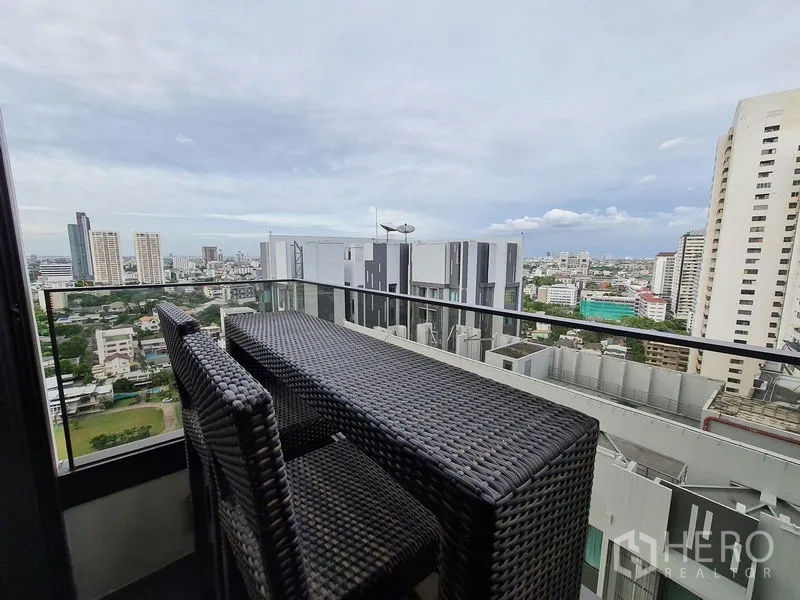 公寓 出租 - 阳台设藤编吧台与高脚椅，玻璃栏杆眺望曼谷全景。