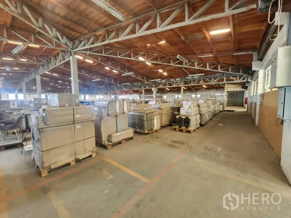 Factory for rent in Mueang Samut Sakhon, Samut Sakhon - Wide warehouse floor with stacks of pallets and fluorescent lighting.