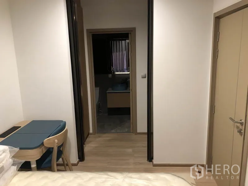 Condominium for rent in Watthana, Bangkok - Hallway from bedroom to bathroom with a built-in study nook and light wood flooring.