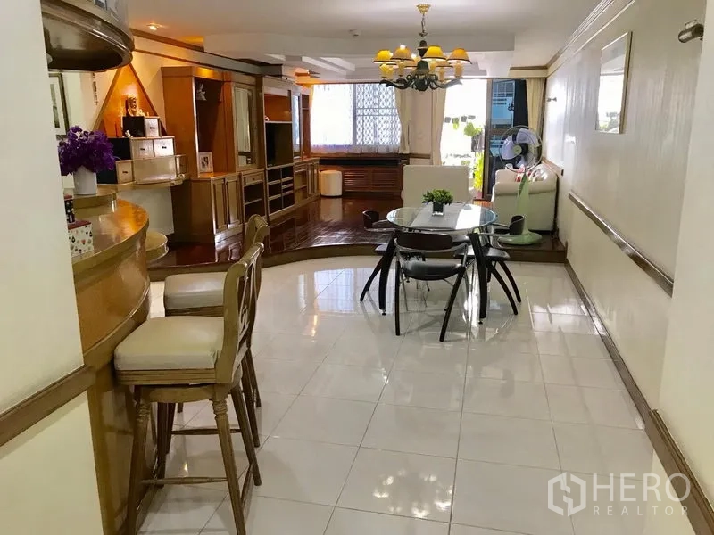 公寓 出租在Watthana, Bangkok - 开放式餐客厅，瓷砖地面衔接木地板，内置吧台与吊灯的曼谷公寓。
