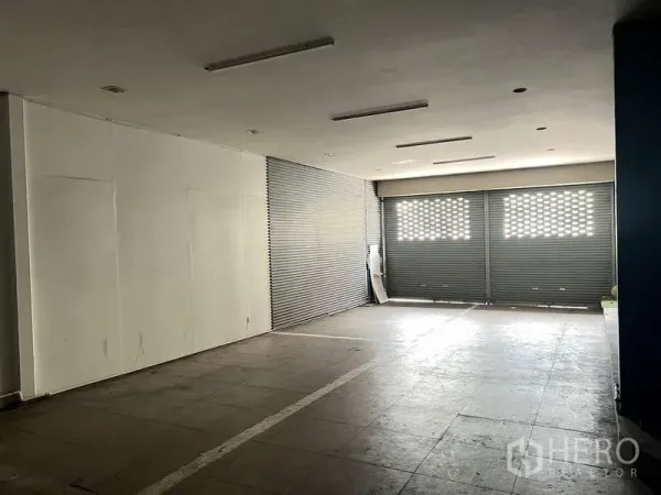 Retail Space for rent in Phaya Thai, Bangkok - Spacious ground-floor retail hall with tiled floor, ceiling lights and wide roller-shutter frontage.