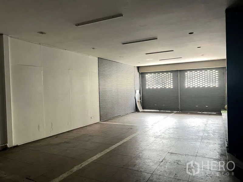 Retail Space for rent in Phaya Thai, Bangkok - Spacious ground-floor retail hall with tiled floor, ceiling lights and wide roller-shutter frontage.