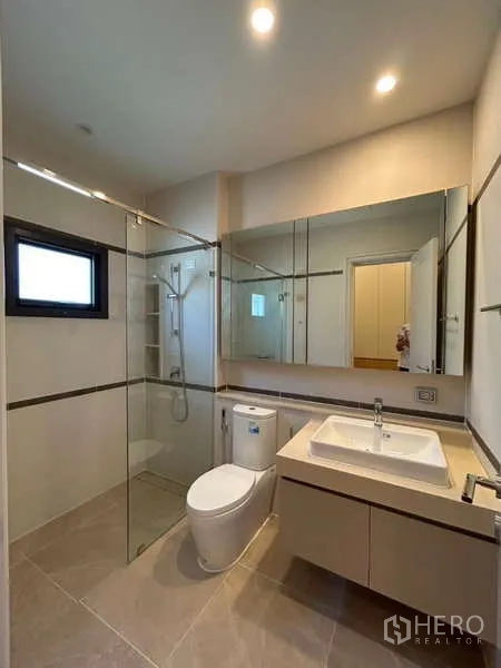 Detached House for sale in Bang Kapi, Bangkok - Contemporary bathroom with glass-enclosed shower, vanity and toilet.