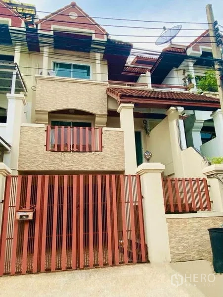 联排别墅 出租或出售在Prawet, Bangkok - 三层联排别墅外立面，红瓦屋顶、阳台与安全铁门。