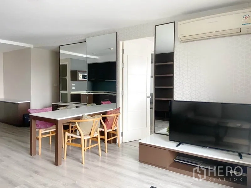 คอนโด ให้เช่าในWatthana, Bangkok - โต๊ะอาหารข้างผนังกระจกเงา หันหน้าไปยังชั้นวางทีวี พร้อมทางเข้าครัว.