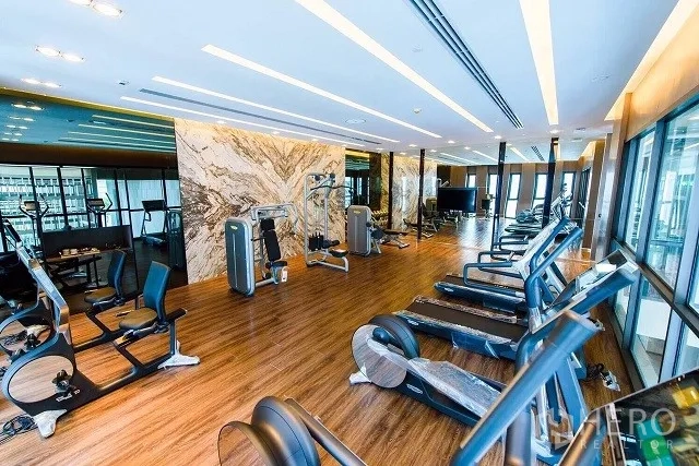 公寓 出租或出售在Watthana, Bangkok - 公寓健身房，配备多种有氧器械与力量设备，木地板和城市景观。