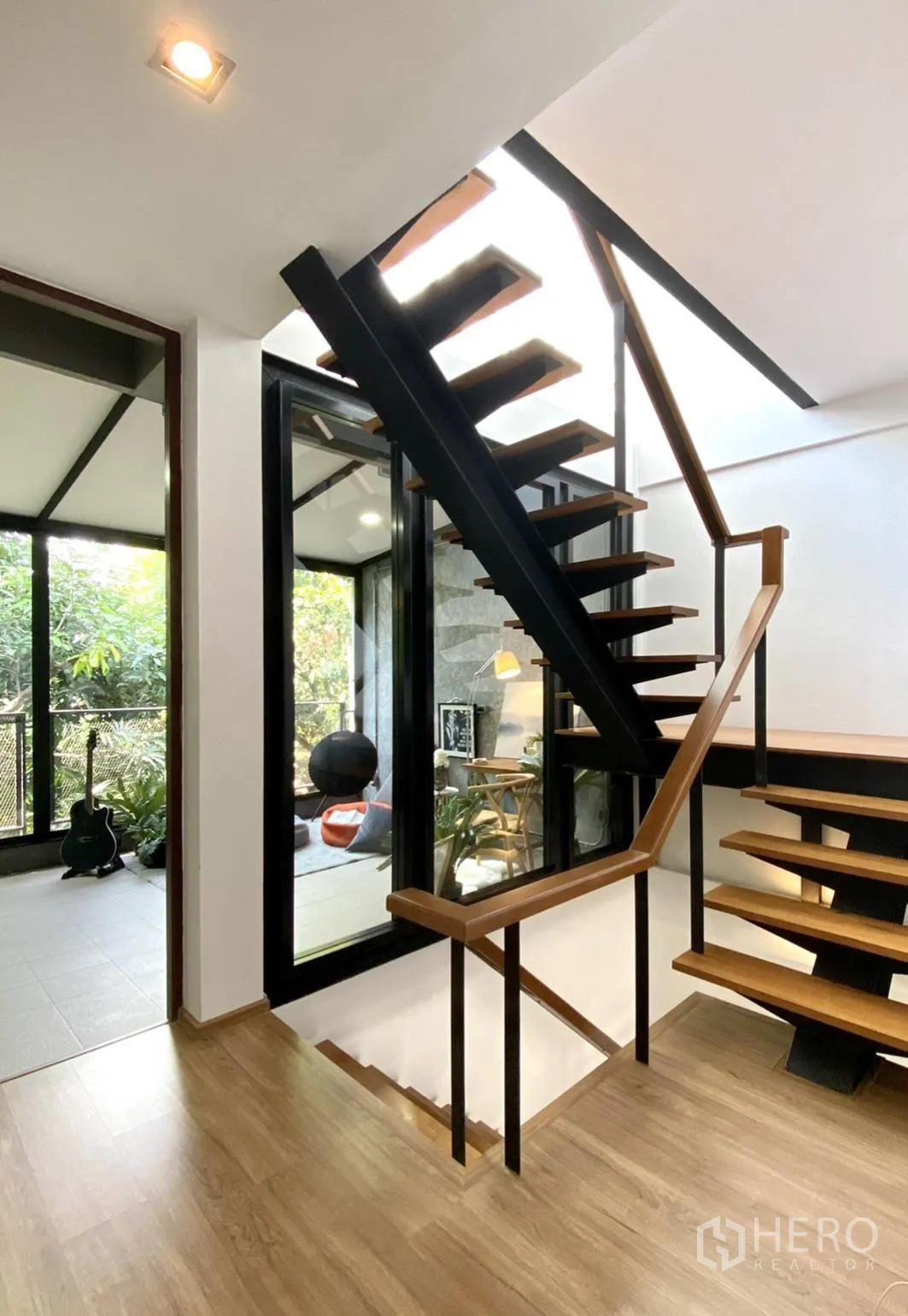 Townhouse for rent in Watthana, Bangkok - Open-tread staircase beside a glass-walled sunroom with garden views.