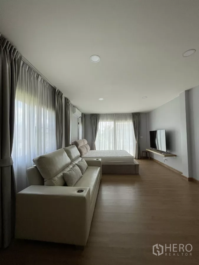 独立式住宅 出租在Bang Phli, Samut Prakan - 主卧侧视，电视墙与落地窗帘。